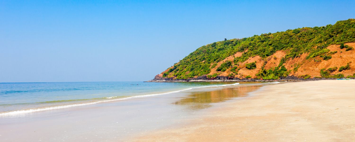 Scenic View of Anjuna Beach: Tranquil Shoreline and Azure Waters